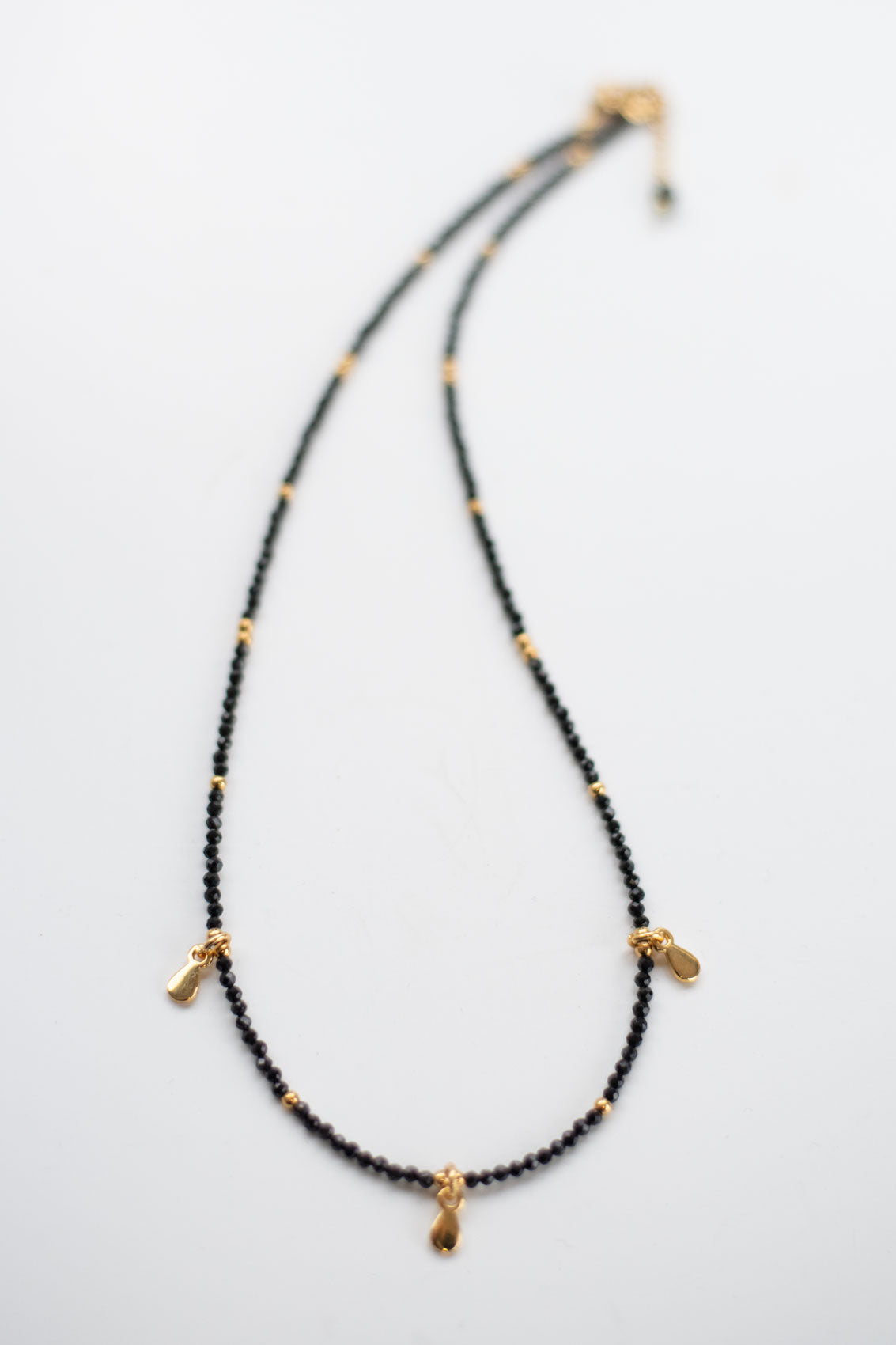 Collier en Spinelle Noire & Breloque en Acier Doré – Élégance Protectrice